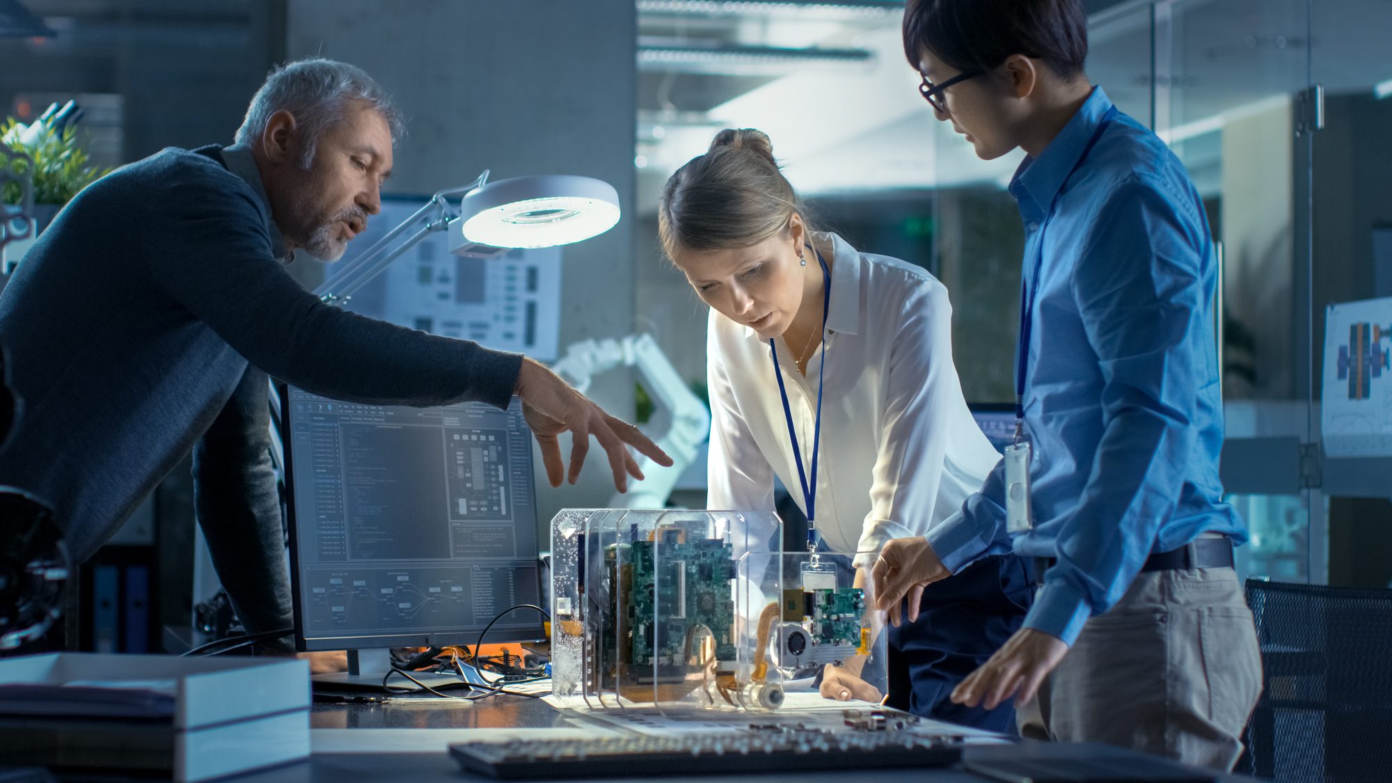 Team Of Computer Engineers Lean On The Desk And Choose